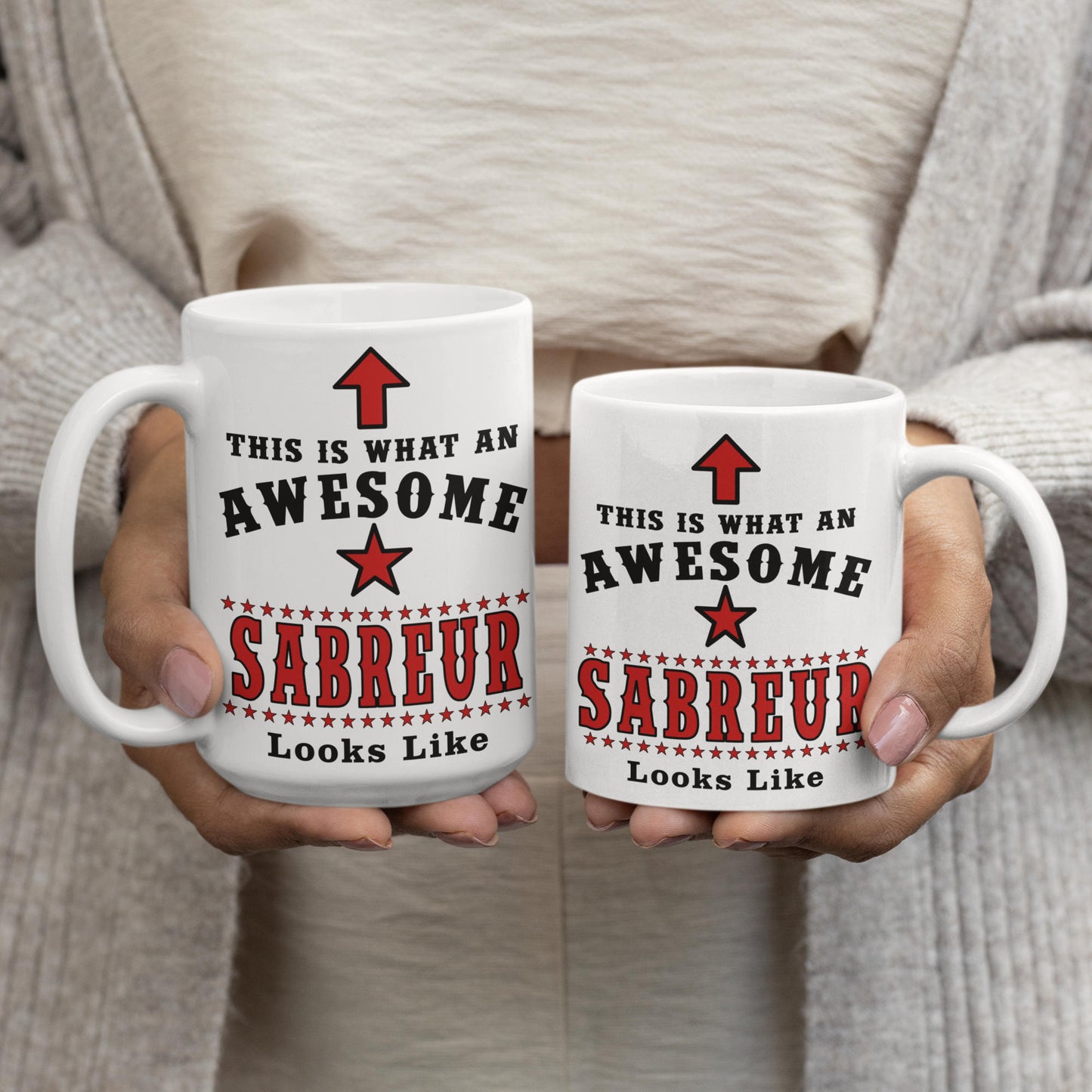 Two Awesome Sabreur mugs, 15oz and 11oz, held side by side showing size comparison