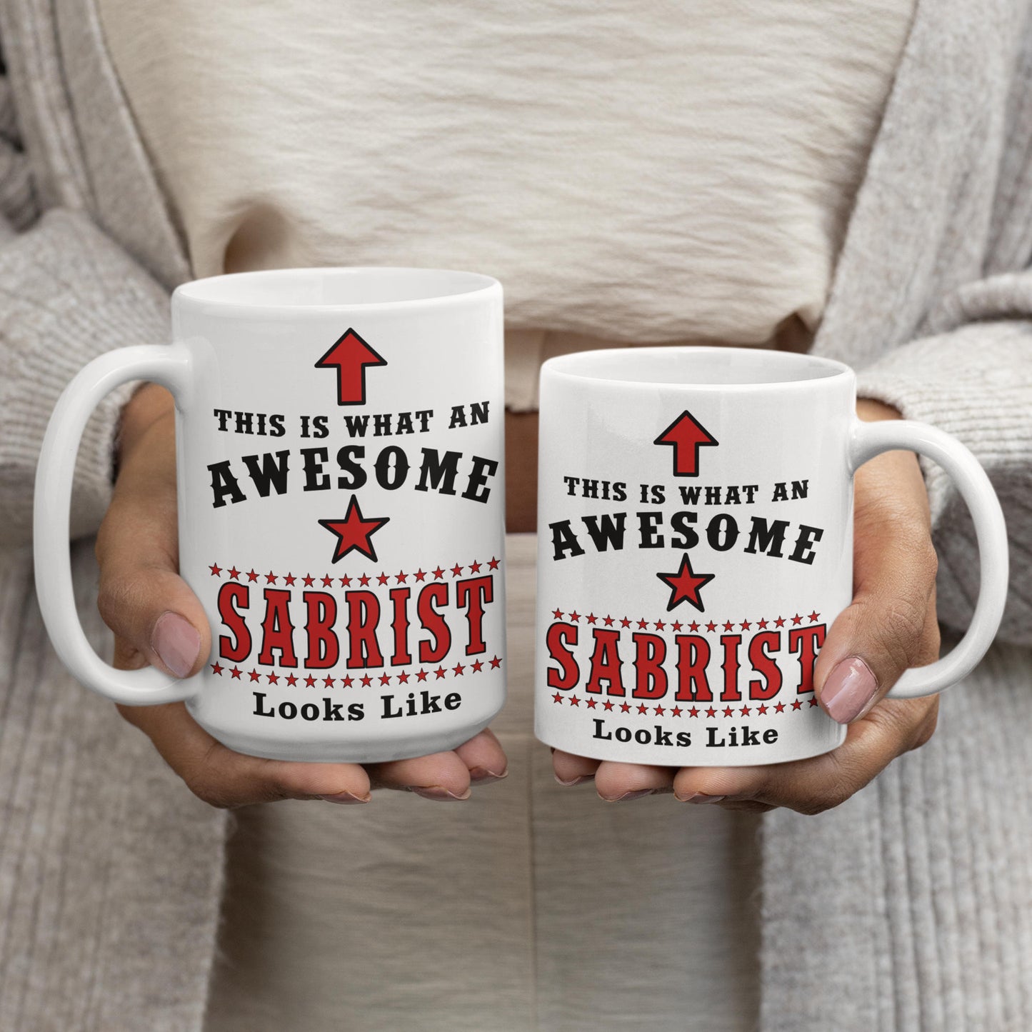 Comparison of 15oz and 11oz "Awesome Sabrist" fencing mugs held side by side, showing size difference of the sabre fencing gift mug