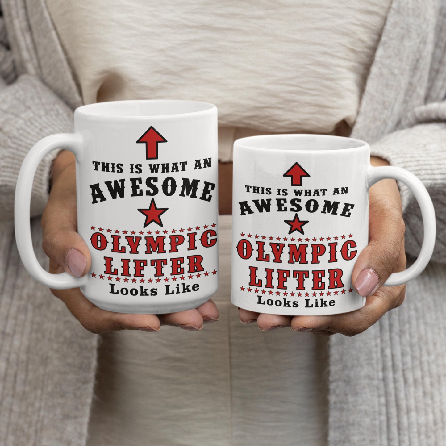 Size comparison of 15oz and 11oz "This is what an awesome Olympic lifter looks like" mugs held side by side, showing the larger 15oz mug on the left next to the smaller 11oz mug