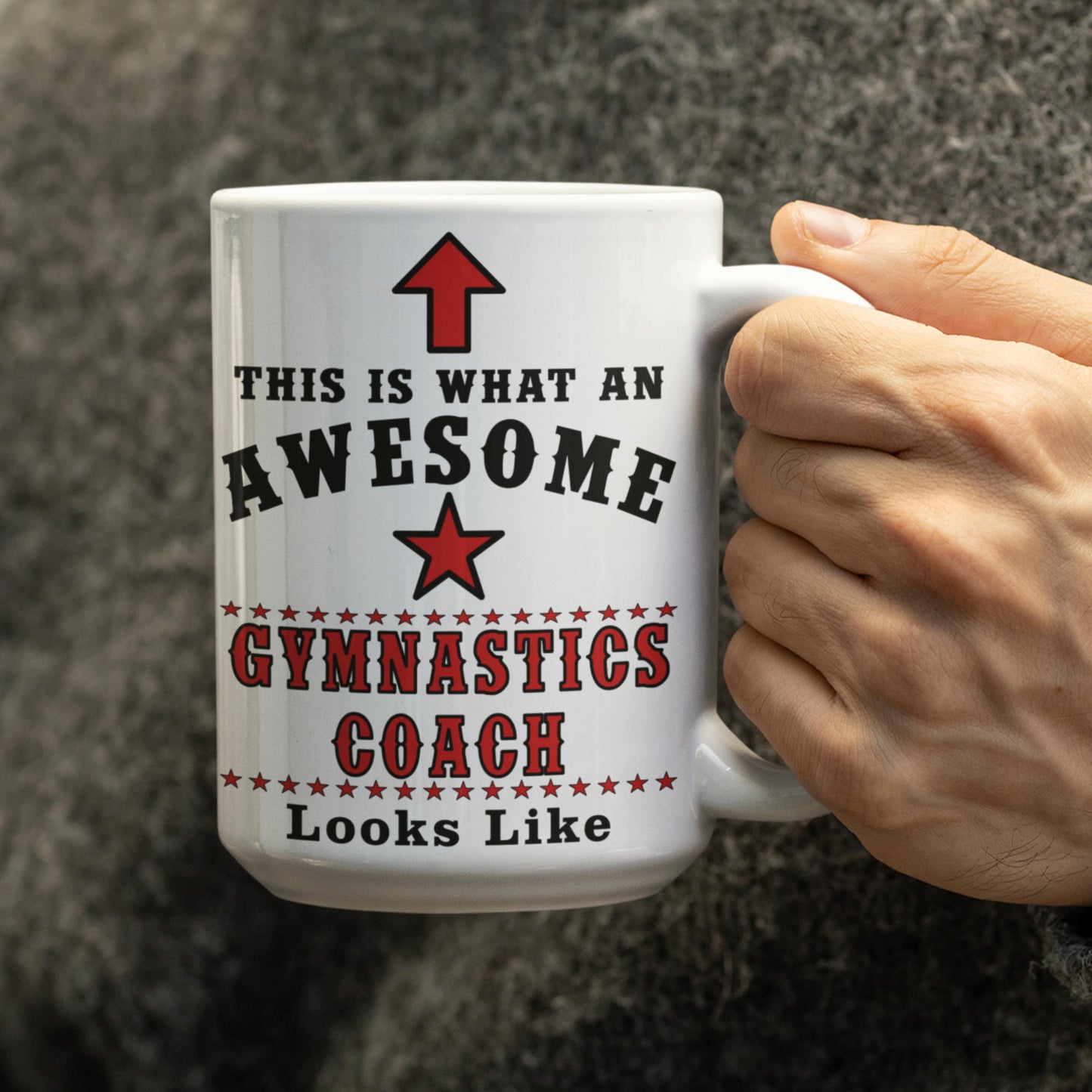Hand holding white 15oz Awesome Gymnastics Coach mug with red star and "This Is What An Awesome Gymnastics Coach Looks Like" text
