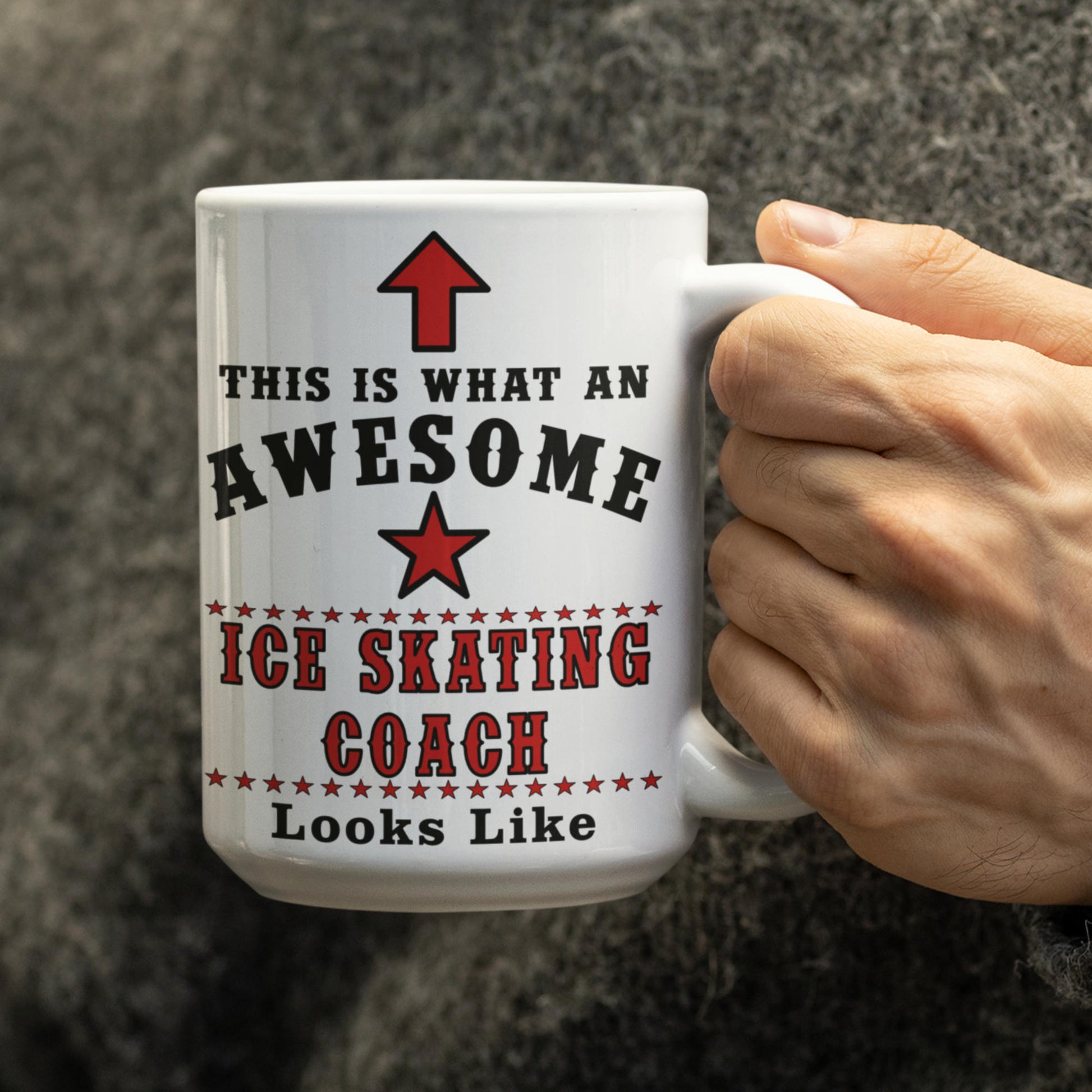 White 15oz mug held in hand printed with 'This Is What An Awesome Ice Skating Coach Looks Like' text and red star design