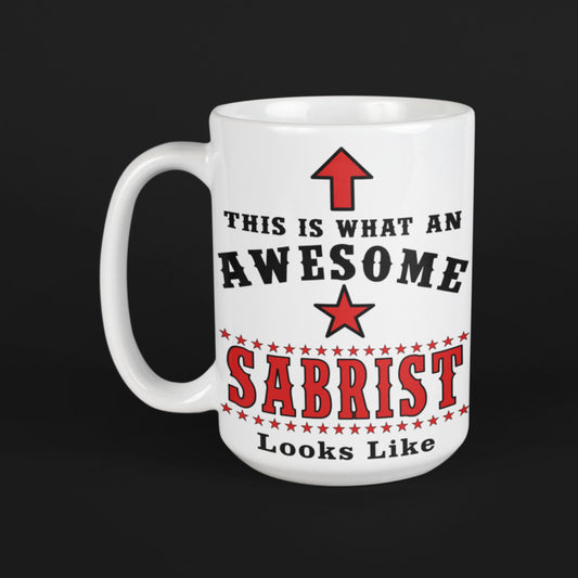 White 15oz ceramic mug on black background featuring red arrow, star and "This is what an awesome Sabrist looks like" fencing quote