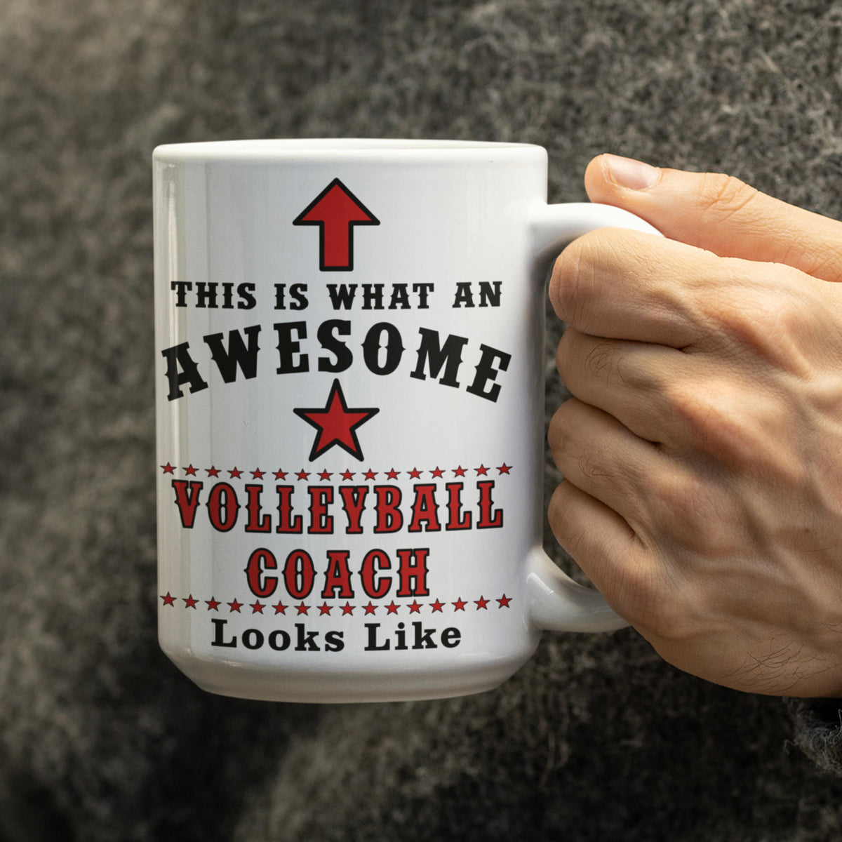 Hand holding a white 15oz volleyball coach mug printed with "This is what an awesome Volleyball Coach looks like"
