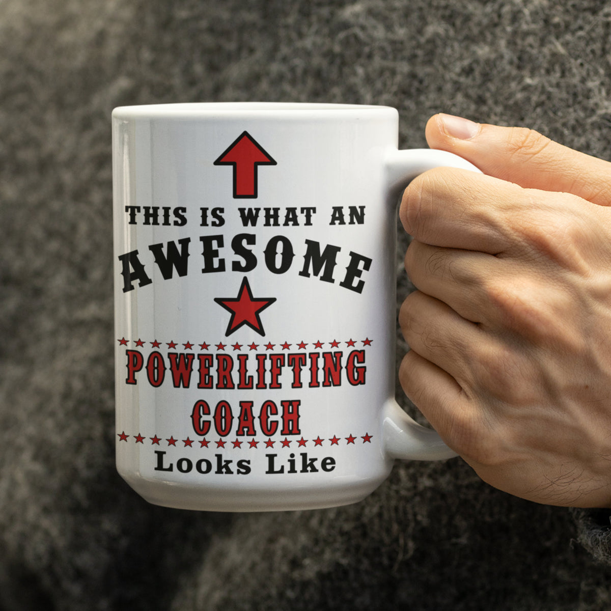 Hand holding a white 15oz mug with black and red "Awesome Powerlifting Coach" design and red arrow and star graphic