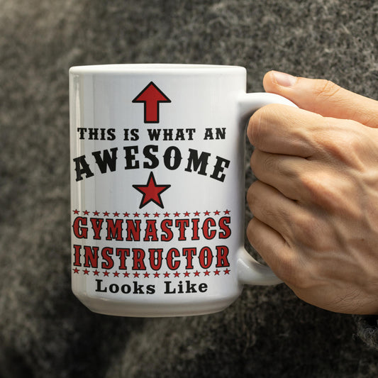 Close-up of hand holding white 15oz mug with 'This is what an Awesome Gymnastics Instructor looks like' text and red star design