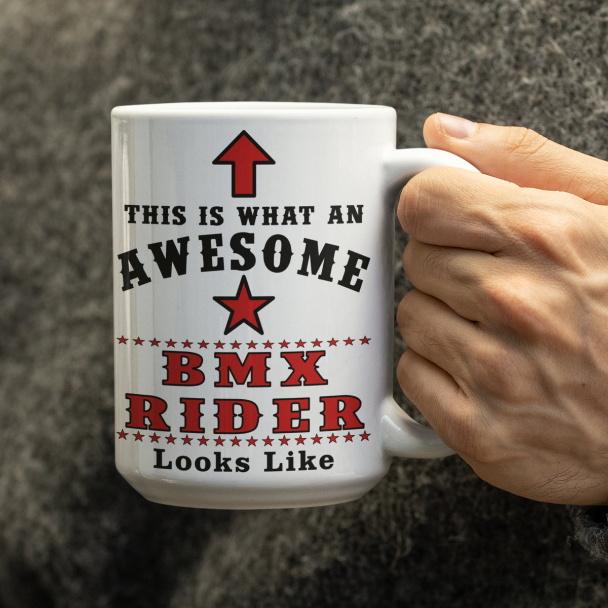 Close-up of hand holding a white 15oz mug printed with "This Is What An Awesome BMX Rider Looks Like" in red and black text