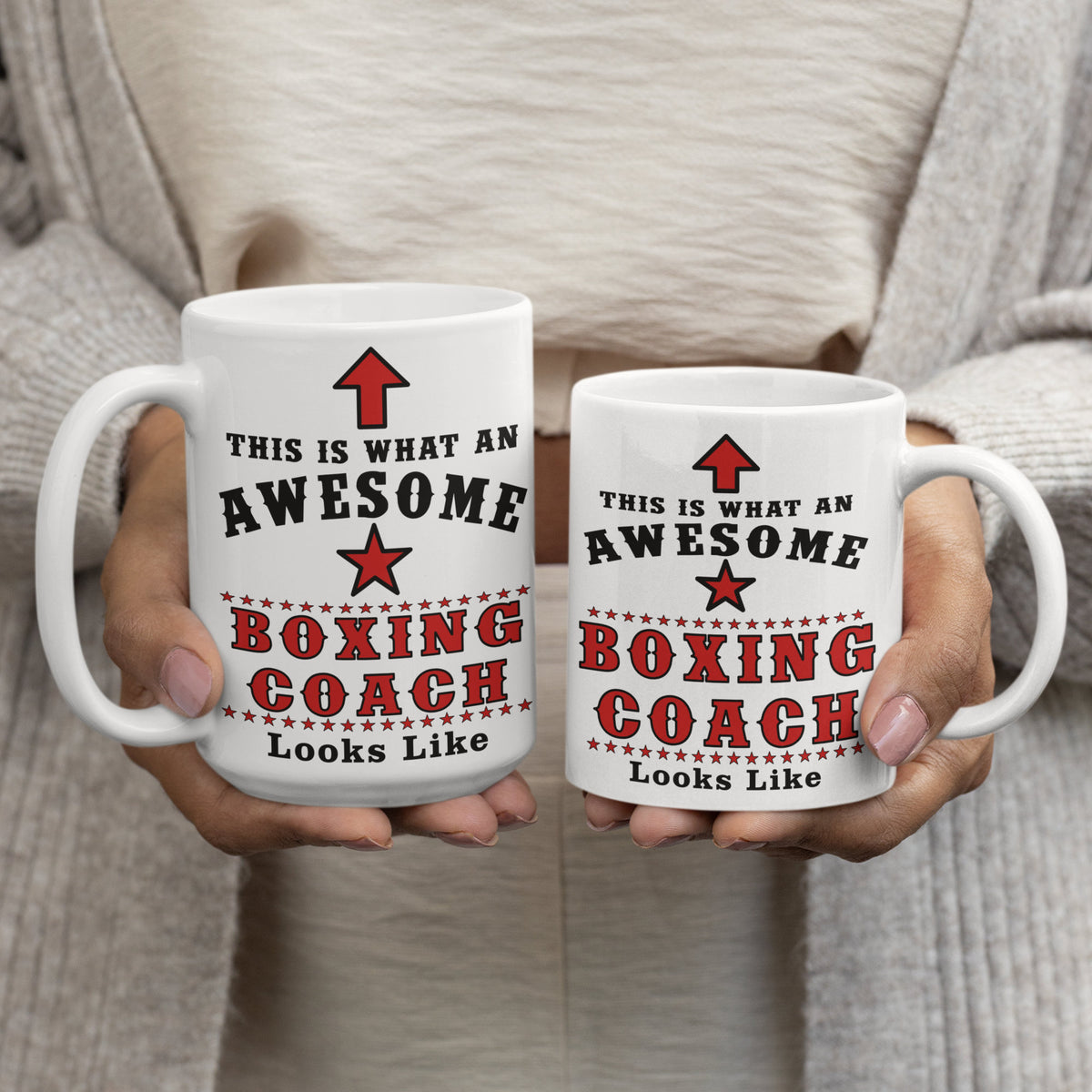 Two white ceramic mugs printed with "This is what an awesome Boxing Coach looks like" text, 15oz and 11oz size comparison, held in hands