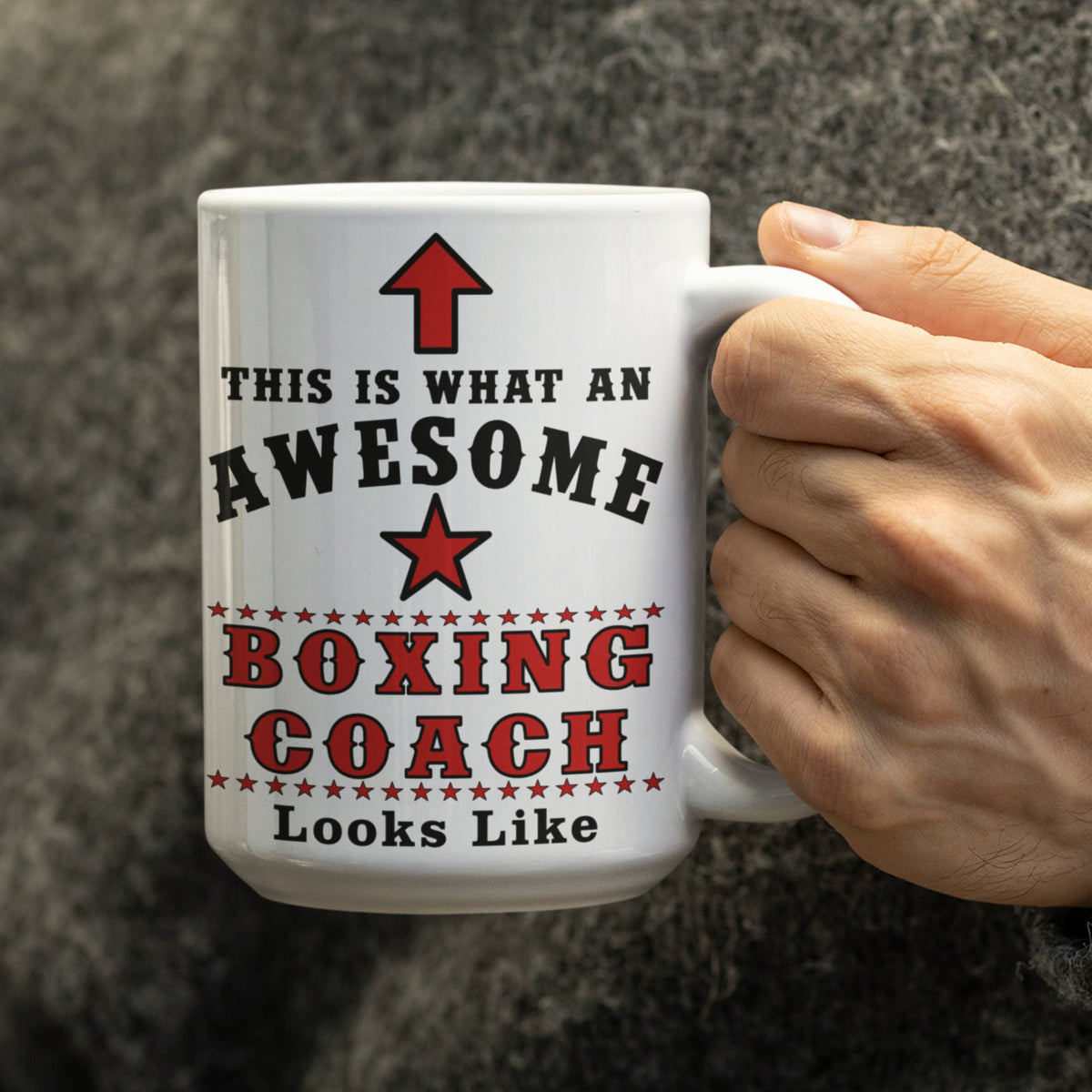 Close-up of 15oz white mug with red and black "This is what an awesome Boxing Coach looks like" design, held in hand