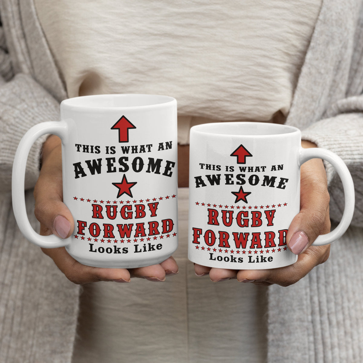 Woman holding two white 15oz and 11oz mugs printed with "This Is What An Awesome Rugby Forward Looks Like" text and red star design, comparing mug sizes