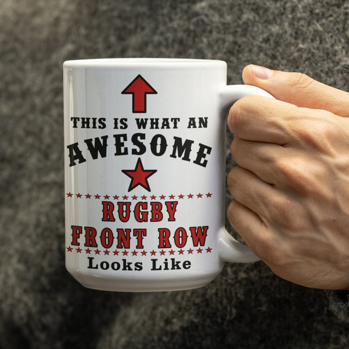 Close-up of hand holding 15oz white Rugby Front Row mug with red star and "This Is What An Awesome Rugby Front Row Looks Like" text