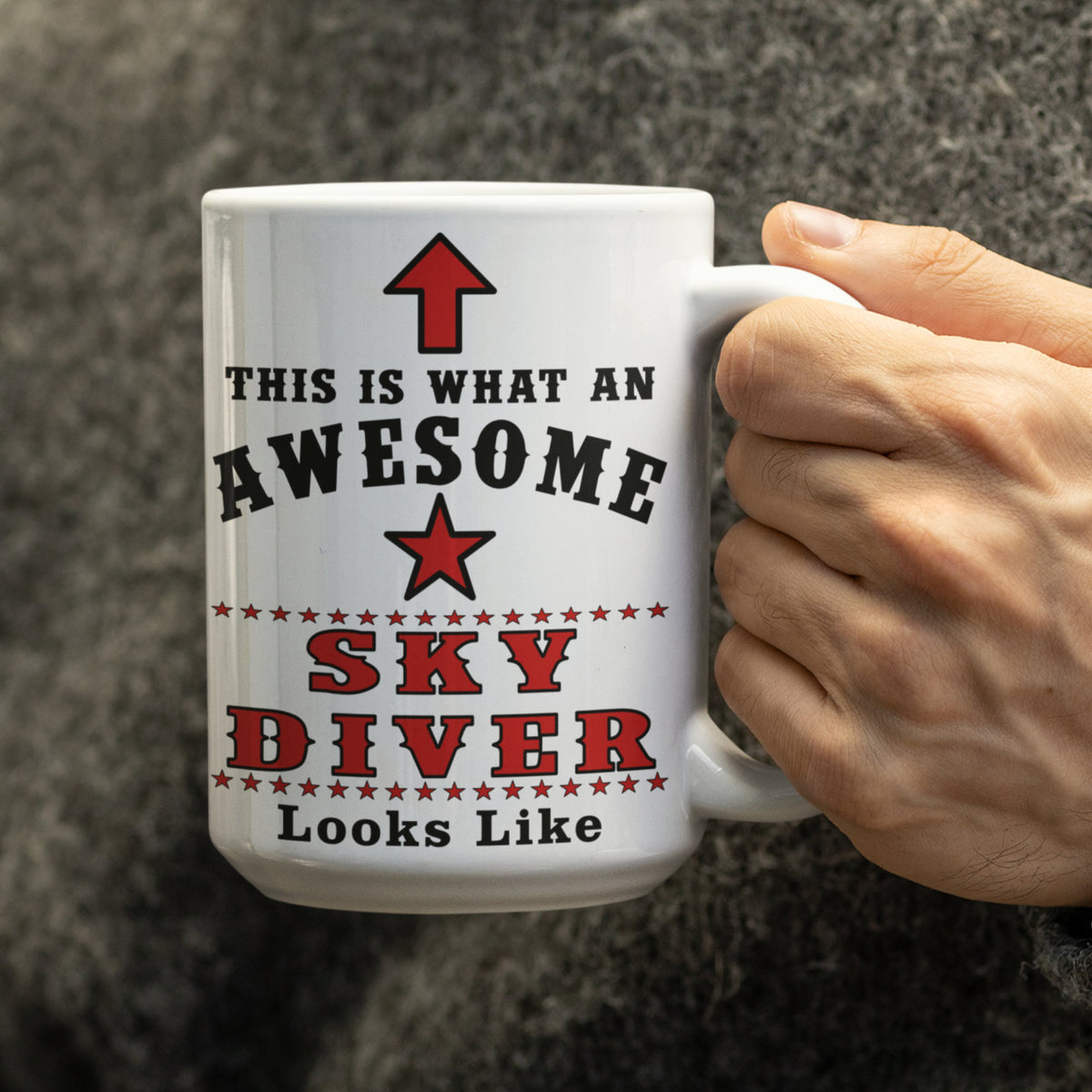 Man in a grey jumper holding the 15oz Awesome Sky Diver mug with red arrow and star design