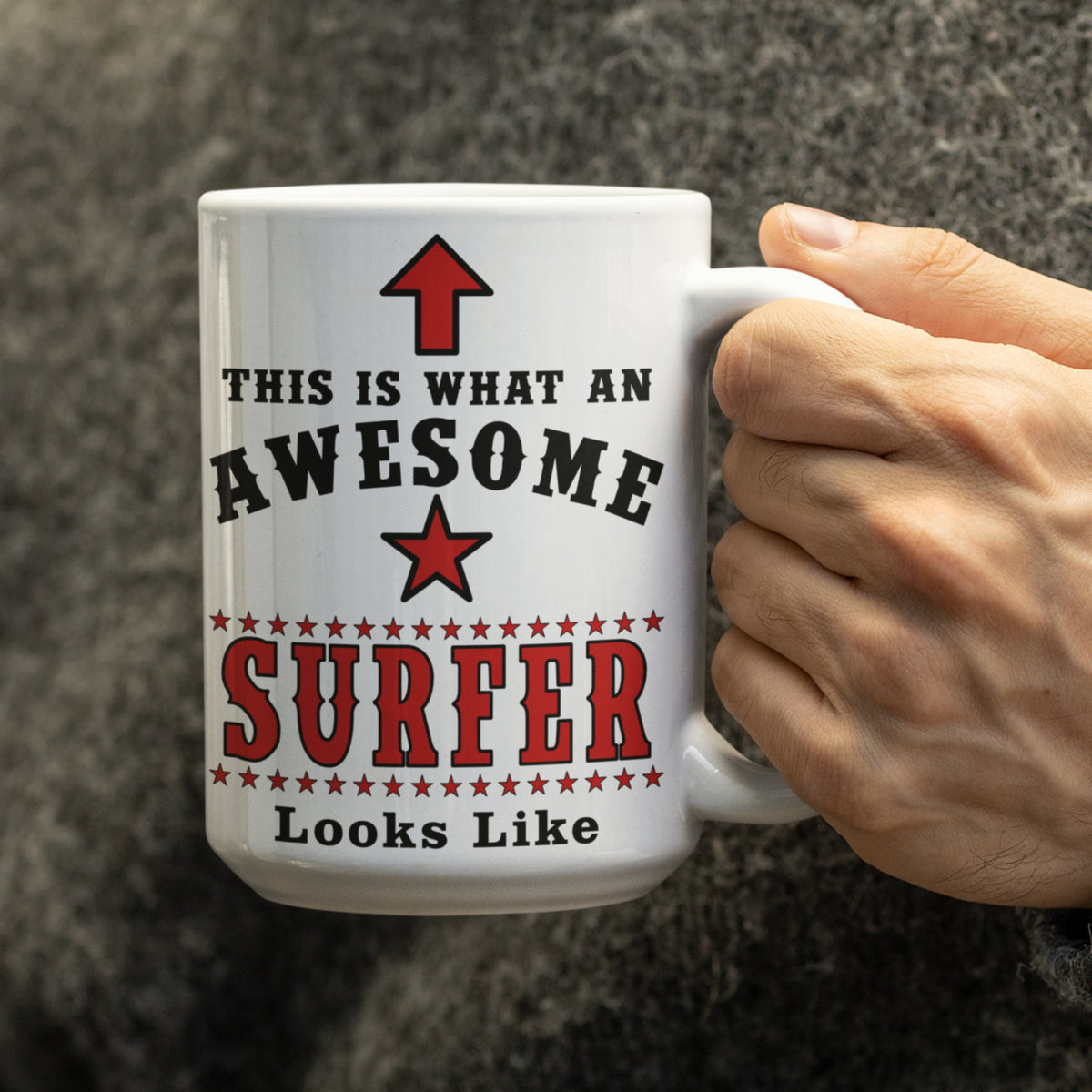 Close-up of hand holding a white 15oz surfer mug with red and black "Awesome Surfer" text design