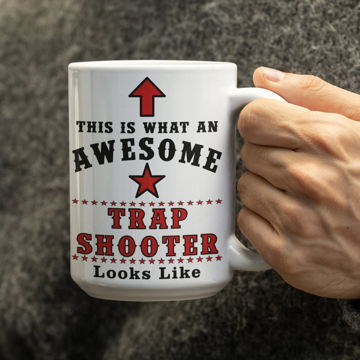 Hand holding a 15oz white mug printed with "This Is What An Awesome Trap Shooter Looks Like" and red star design